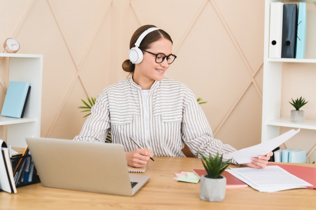 Freelancer designer listening to music at workplace in office doing paperwork, working with document